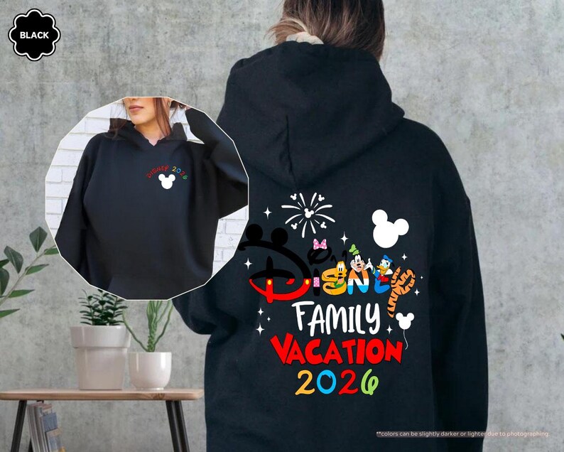 Puede incluir: Una sudadera con capucha negra que presenta un gr&aacute;fico en la parte posterior con el texto Disney Family Vacation 2026, personajes de dibujos animados coloridos y fuegos artificiales. Una versi&oacute;n m&aacute;s peque&ntilde;a est&aacute; en el pecho izquierdo.