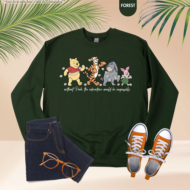 Puede incluir: Una sudadera verde bosque con un dise&ntilde;o de Winnie the Pooh y sus amigos. El dise&ntilde;o incluye a Pooh, Tigger, Eeyore y Piglet, con el texto "without Pooh the adventure would be impossible." La sudadera se combina con vaqueros azules y zapatillas naranjas.