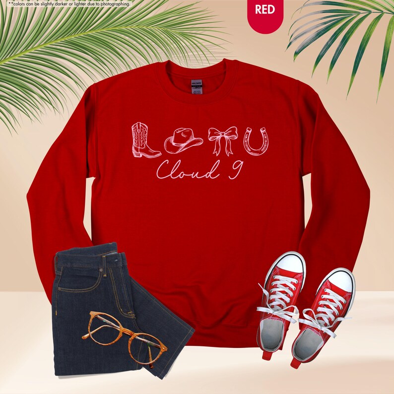 May include: A red sweatshirt with white text reading "LOTU Cloud 9", featuring a cowboy boot, hat, bow, and horseshoe. The image also shows a pair of blue jeans, gold-rimmed glasses, and red trainers.