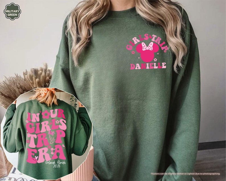 Peut inclure: Sweat-shirt vert militaire avec un motif rose sur le devant indiquant "GIRLS TRIP" avec un n&oelig;ud Minnie Mouse et le nom "DANIELLE". Le dos du sweat-shirt porte l'inscription "IN YOUR GIRLS TRIP ERA" et "Orlando, Florida 2026".