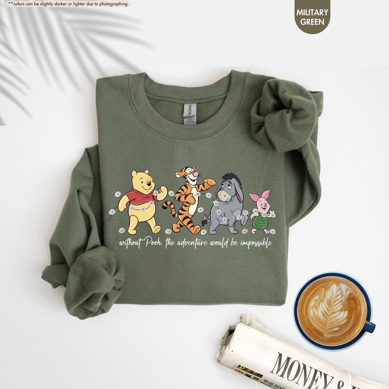 Puede incluir: Sudadera verde militar con Winnie the Pooh, Tigger, Eeyore y Piglet. La frase "without Pooh the adventure would be impossible" est&aacute; impresa debajo de los personajes. La sudadera tiene cuello redondo y mangas largas.