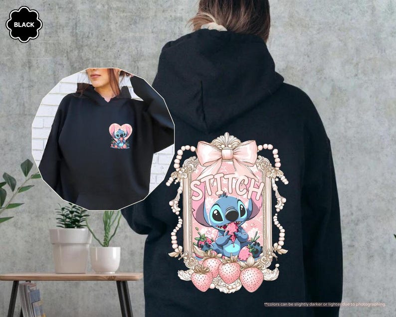 Puede incluir: Sudadera con capucha negra con un gr&aacute;fico de Stitch en la espalda y una versi&oacute;n m&aacute;s peque&ntilde;a en la parte delantera. El gr&aacute;fico de la espalda incluye un lazo rosa, la palabra "Stitch" y fresas. El gr&aacute;fico frontal es un coraz&oacute;n con Stitch.