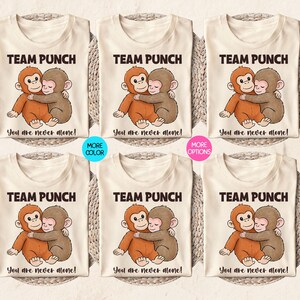 May include: Cream-colored t-shirts with a cartoon illustration of two hugging monkeys. The text "TEAM PUNCH" is above the image, and "You are never alone!" is below. Additional color and option variations are also shown.