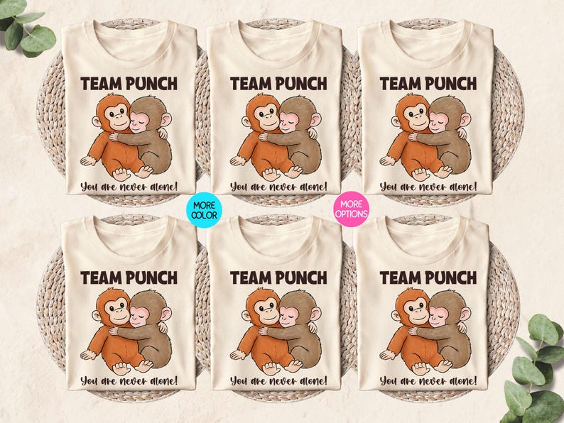 May include: Cream-colored t-shirts with a cartoon illustration of two hugging monkeys. The text "TEAM PUNCH" is above the image, and "You are never alone!" is below. Additional color and option variations are also shown.