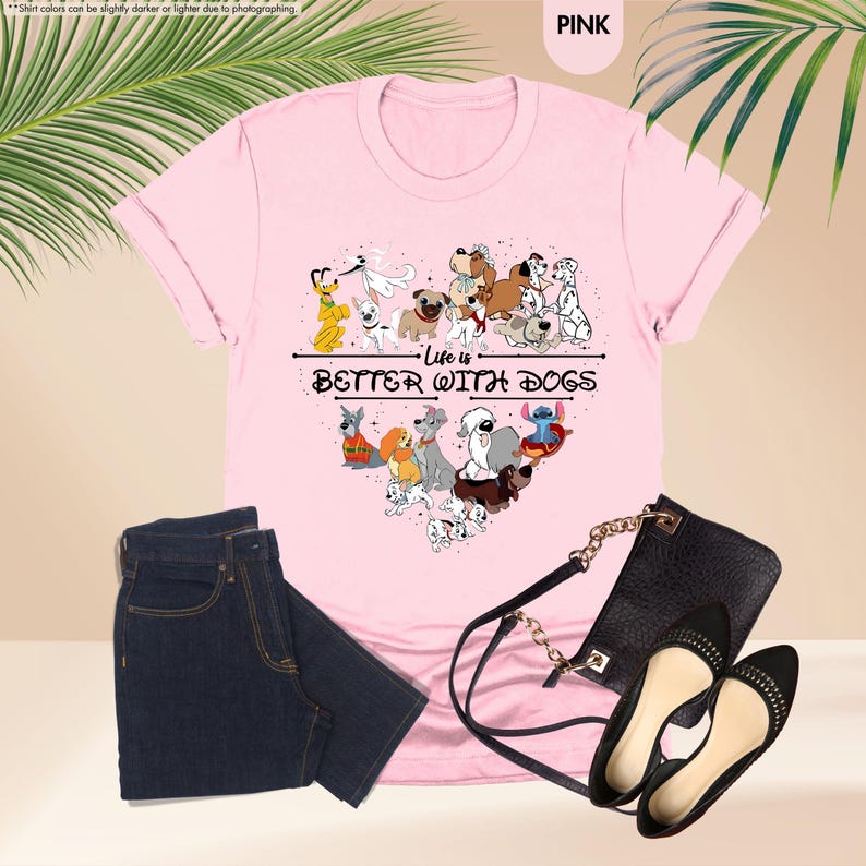 May include: Pink t-shirt with a heart-shaped graphic of various cartoon dogs and the text "Life is Better With Dogs." The shirt is paired with dark blue jeans, a black purse, and black flats.