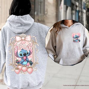 Puede incluir: Sudadera con capucha gris deportivo con un gr&aacute;fico de Stitch. El dise&ntilde;o trasero incluye una ilustraci&oacute;n enmarcada de Stitch con un lazo rosa, la palabra "Stitch" y fresas. Un gr&aacute;fico de Stitch m&aacute;s peque&ntilde;o est&aacute; en la parte delantera. La sudadera tiene capucha con cord&oacute;n y bolsillo de canguro.