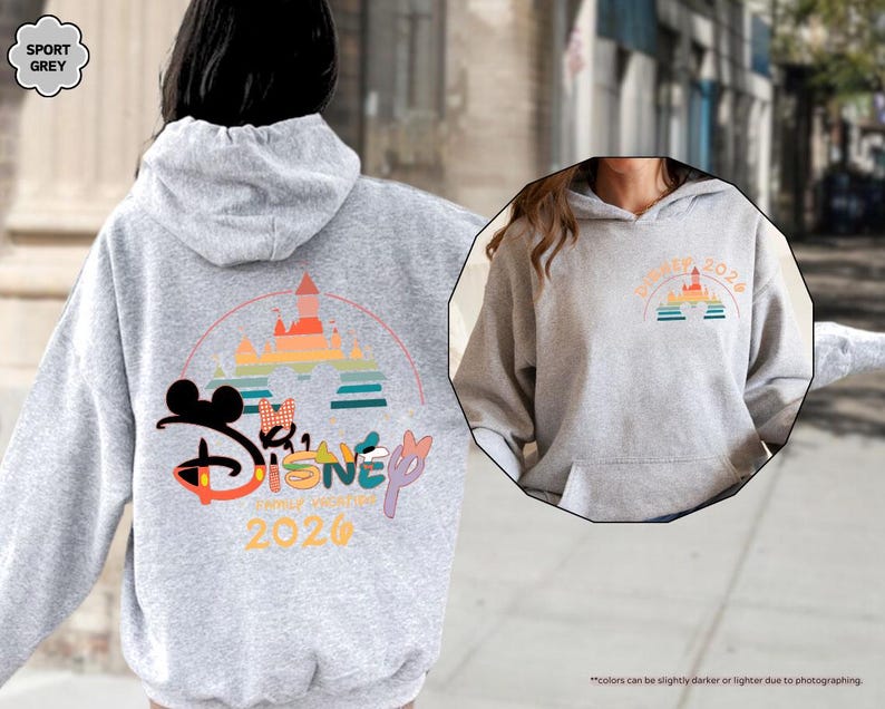 May include: A light gray hoodie with a front pocket and a hood. The back features a colorful Disney graphic with a castle, Mickey Mouse ears, and the text "Disney Summer Vacation 2026". The front has a smaller matching graphic.