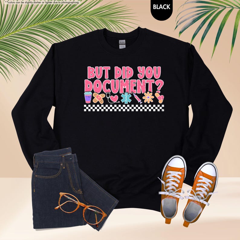 Puede incluir: Sudadera negra con el texto "BUT DID YOU DOCUMENT?" en rosa y blanco, junto con gr&aacute;ficos m&eacute;dicos. La imagen tambi&eacute;n muestra unos vaqueros azules, gafas naranjas y zapatillas deportivas naranjas.