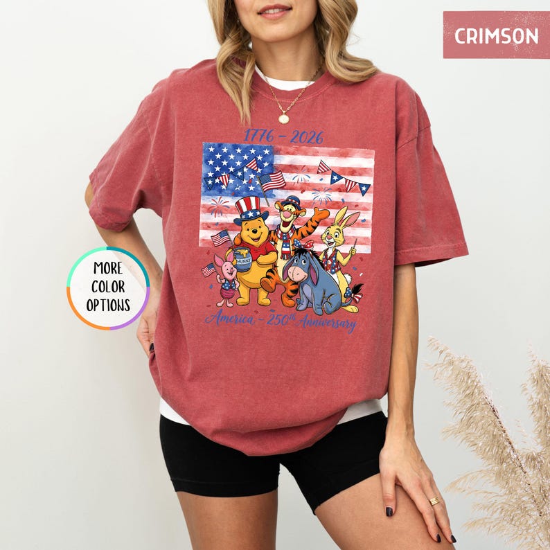 May include: Crimson-colored t-shirt featuring a graphic of Winnie the Pooh and friends celebrating the American flag. The shirt includes the text "1776-2026" and "America - 250th Anniversary".