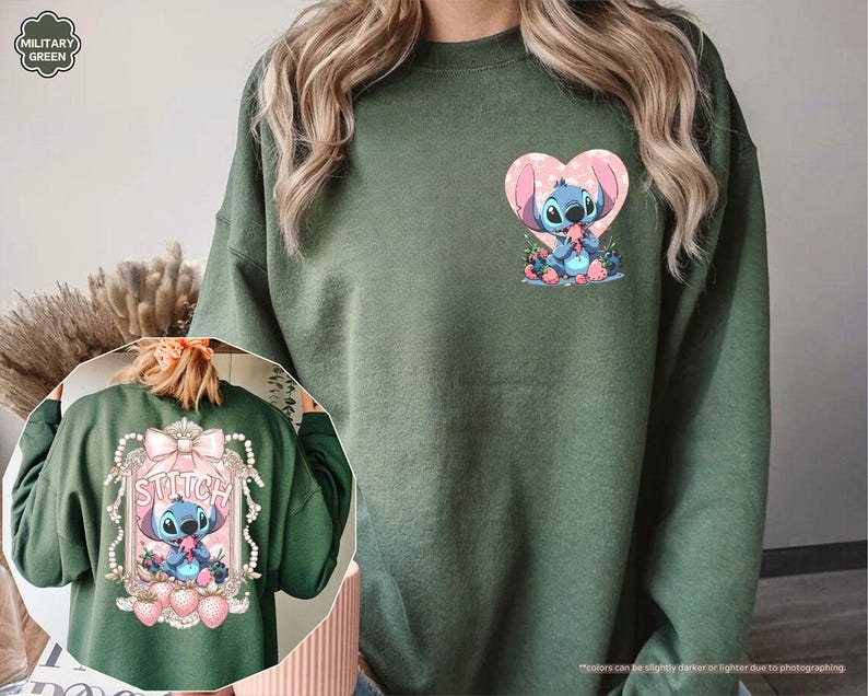 Puede incluir: Sudadera verde militar con un dise&ntilde;o de Stitch. La parte delantera muestra a Stitch dentro de un coraz&oacute;n rosa, mientras que la parte trasera presenta a Stitch dentro de un marco decorativo con la palabra "Stitch". El dise&ntilde;o incluye fresas rosas y flores azules.
