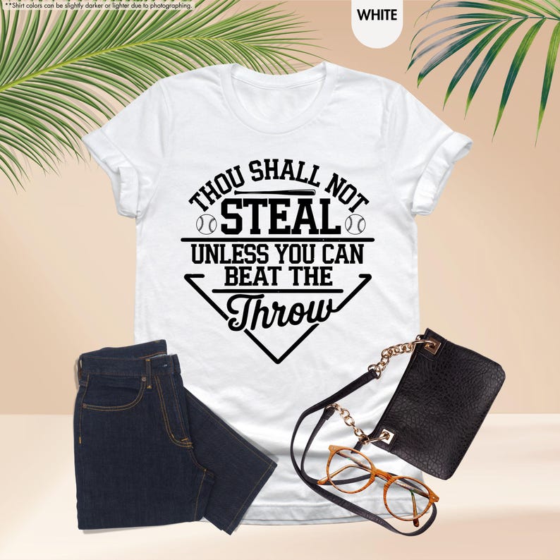 May include: White t-shirt with the text "Thou Shall Not Steal Unless You Can Beat The Throw" in black. The shirt is paired with dark blue jeans, a black purse, and eyeglasses.