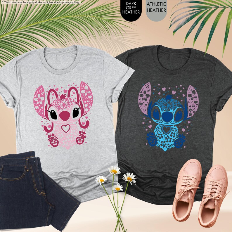 May include: Two t-shirts with a cartoon character design. One is light gray with a pink design, and the other is dark gray with a blue design. The designs feature a heart-shaped face and floral accents. A pair of blue jeans and pink sneakers are also visible.