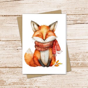 May include: A watercolor illustration of a cute fox wearing a red and white scarf. The fox is sitting on a white background with a few brown leaves.