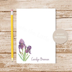 May include: A personalized notepad with a watercolor illustration of purple irises. The notepad has 50 sheets and says "Carolyn Brennan" at the bottom.