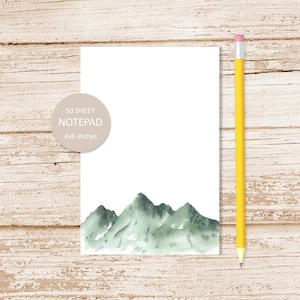 May include: A 50-sheet notepad with a watercolor illustration of green mountains on the front. The notepad is 4x6 inches.