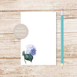 May include: A white notepad with a blue hydrangea illustration and the text "50 SHEET NOTEPAD 4x6 inches" in a circle.