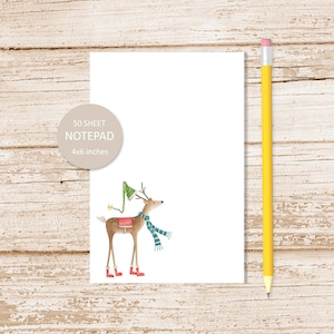 May include: A notepad with a whimsical watercolor illustration of a reindeer wearing a scarf, hat, and boots. The notepad is 4x6 inches and has 50 sheets. A yellow pencil with a pink eraser is next to the notepad. The notepad is on a white surface.