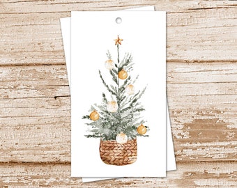 May include: Watercolor Christmas tree gift tags. The tags feature a hand-painted Christmas tree with gold ornaments and a star on top, set in a woven basket. The tags are on a white background.