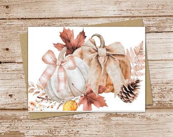 May include: A watercolor illustration of two pumpkins with fall foliage. One pumpkin is white with a pink and white plaid bow, and the other is brown with a beige bow. The pumpkins are surrounded by fall leaves, including a maple leaf and fern fronds.