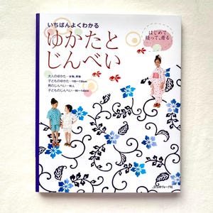 May include: A book titled "Yukata and Jinbei" with Japanese text and illustrations. The cover features children in traditional Japanese clothing, with blue floral and vine designs. The book's title is in Japanese.