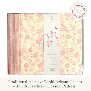 May include: A pack of square origami paper sheets featuring a light cream background with a repeating pink cherry blossom pattern. A central white paper band displays the text Sakura, Origami, 15cm x 15cm, 21 sheets, and 7 colors x 3 sheets.