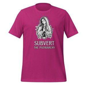 May include: A pink t-shirt featuring a black and white image of the Virgin Mary with the text "Subvert the Patriarchy" printed below.