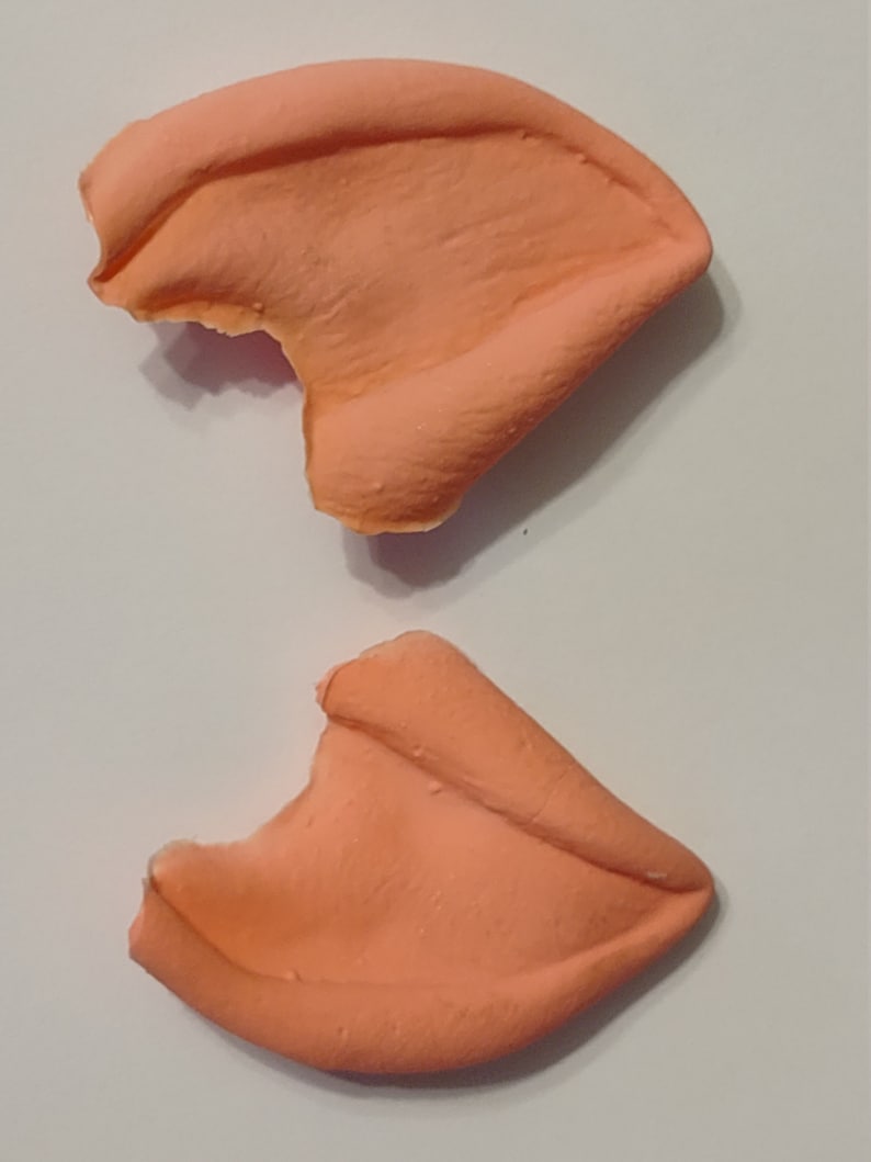 May include: Two peach-colored silicone ear molds, each with a small bite taken out of the top edge.