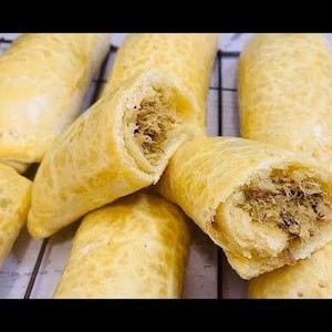 Può includere: Primo piano di diversi pasticcini dorati e marroni ripieni di carne trita. I pasticcini sono disposti su una griglia.