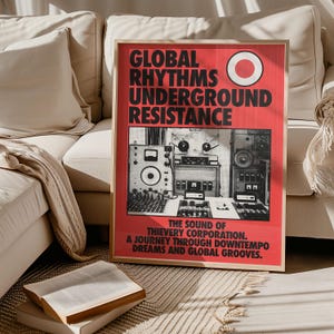 Puede incluir: Un póster enmarcado con fondo rojo y texto negro que dice "GLOBAL RHYTHMS UNDERGROUND RESISTANCE". El póster presenta una imagen en blanco y negro de equipos de audio. El texto de abajo dice "THE SOUND OF THIEVERY CORPORATION. A JOURNEY THROUGH DOWNTEMPO DREAMS AND GLOBAL GROOVES."