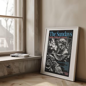 K&ouml;nnte beinhalten: Ein gerahmtes Poster mit dem Titel "The Sundays" und dem Untertitel "Reading, Writing and Arithmetic". Das Poster zeigt ein Schwarz-Wei&szlig;-Bild einer Statue und eine Illustration einer Muschel. Das Poster befindet sich in einem wei&szlig;en Rahmen und lehnt an einer Wand.