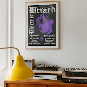 May include: A framed poster featuring the text Electric Wizard in white gothic font, a purple-toned portrait of a person, and a tracklist including Funeralopolis, Return trip, We hate you, Dunwich, Barbarian, I. the witchfinder, Vinum sabbathi, Wizard in black, A chosen few, Stone magnet, Behemoth, and Mourning prayer.