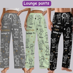 Puede incluir: Tres pares de pantalones de salón con cinturillas con cordón. Uno es gris con el texto "This GRANDMA belongs to" y un patrón de dibujos infantiles. Otro es verde claro con "This MOTHER belongs to." El tercero es negro con "This PAPA belongs to."