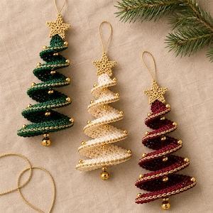 May include: Three spiral-shaped Christmas tree ornaments made of crocheted yarn in dark green, cream, and deep red. Each tree is topped with a small crocheted gold star, decorated with tiny gold beads along the edges, and finished with a gold bell at the base.