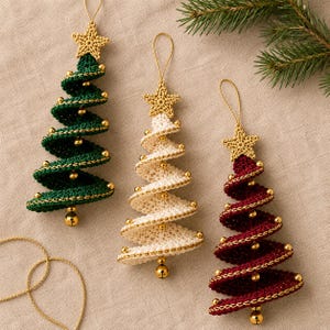 May include: Three spiral-shaped Christmas tree ornaments made of crocheted yarn in dark green, cream, and deep red. Each tree is topped with a small crocheted gold star, decorated with tiny gold beads along the edges, and finished with a gold bell at the base.