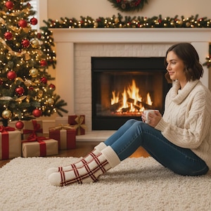 May include: A pair of cream-coloured knit socks featuring a red and gold plaid pattern, worn with blue denim jeans and a cream-coloured cable knit sweater. The socks have a thick, ribbed cuff at the top and a textured, woven appearance throughout.