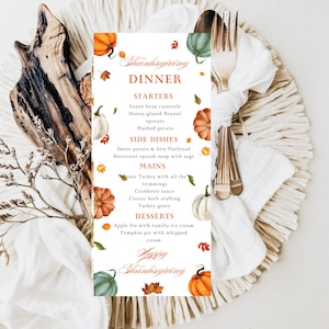 May include: Thanksgiving dinner menu card with watercolor pumpkins and leaves. The menu includes starters, side dishes, mains, and desserts. The card is decorated with a rustic wooden element, a white napkin, and silverware.