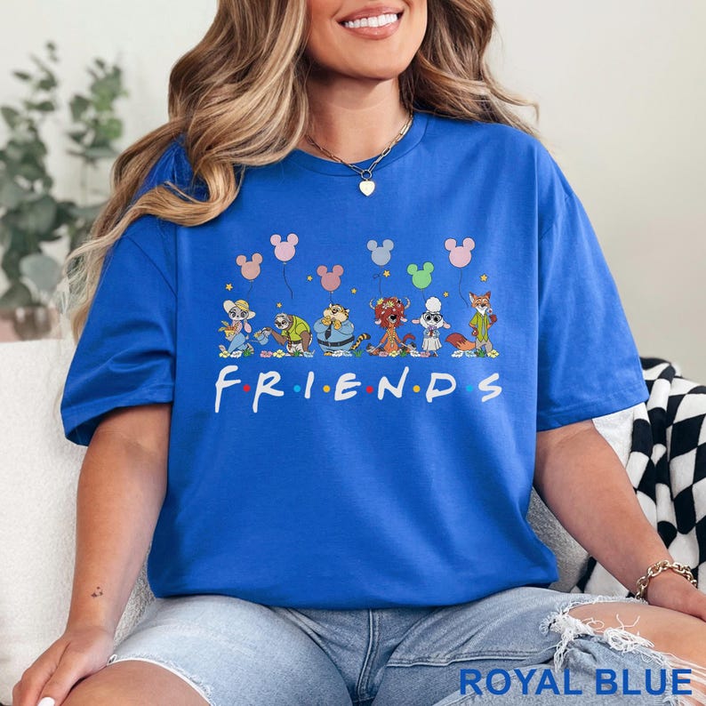 May include: Royal blue t-shirt featuring the word "FRIENDS" in white, with cartoon characters and Mickey Mouse balloon graphics. The shirt is a vibrant blue and has a relaxed fit.