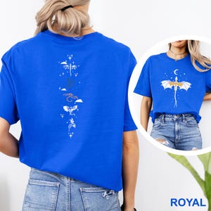 Pu&ograve; includere: T-shirt blu reale con un disegno di drago bianco sul davanti e sul retro. Il design posteriore include una disposizione verticale di draghi stilizzati, nuvole e stelle. Il design anteriore presenta un drago con una luna crescente.