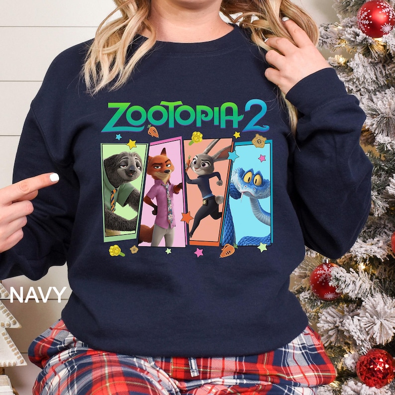 Peut inclure: Sweat-shirt bleu marine avec le texte "ZOOTOPIA 2" et un graphisme color&eacute; des personnages du film d'animation. Le graphisme comprend un paresseux, un renard, un lapin et un serpent. Le mot "NAVY" est imprim&eacute; en bas &agrave; gauche.