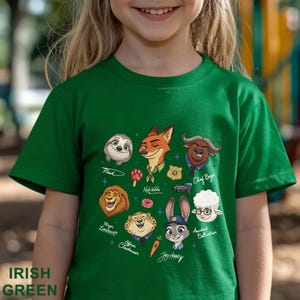 Pu&ograve; includere: T-shirt verde irlandese per bambini con personaggi dei cartoni animati di Zootropolis, tra cui Flash, Nick Wilde e Judy Hopps. La maglietta ha le parole "Irish Green" stampate in basso. Il design include vari personaggi e i loro nomi.