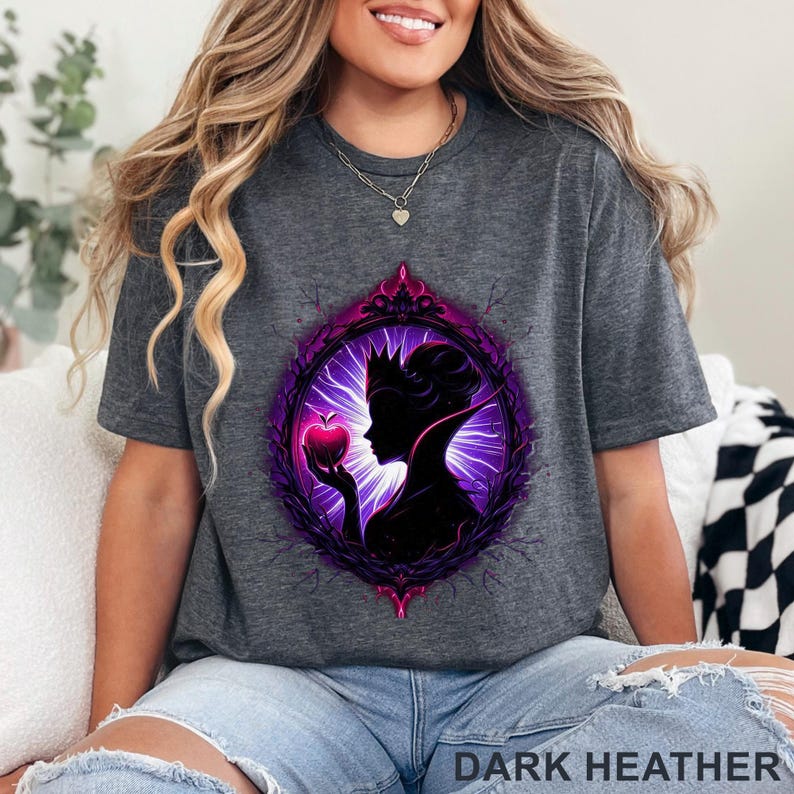 Puede incluir: Camiseta gris oscuro jaspeado con un dise&ntilde;o enmarcado en morado y rosa de una reina sosteniendo una manzana. El texto "DARK HEATHER" est&aacute; impreso en la parte inferior. La camiseta es de estilo c&oacute;modo e informal.