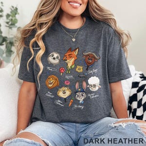 Pu&ograve; includere: T-shirt grigio scuro con illustrazioni di personaggi di cartoni animati di un popolare film d'animazione. La maglietta include personaggi come Flash, Nick Wilde, Judy Hopps e Chief Bogo. Il testo "DARK HEATHER" &egrave; stampato in basso.