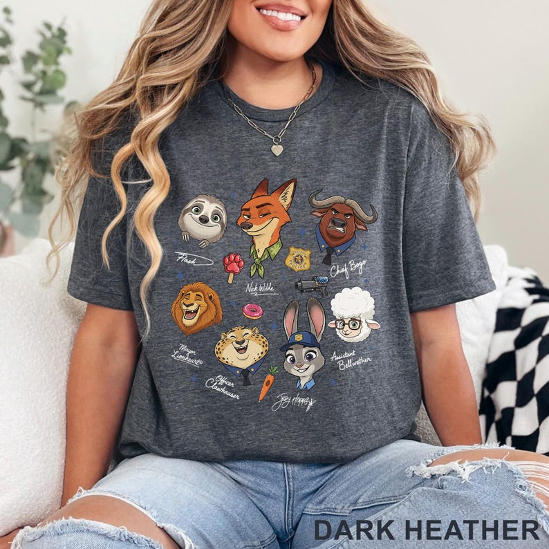 Pu&ograve; includere: T-shirt grigio scuro con illustrazioni di personaggi di cartoni animati di un popolare film d'animazione. La maglietta include personaggi come Flash, Nick Wilde, Judy Hopps e Chief Bogo. Il testo "DARK HEATHER" &egrave; stampato in basso.