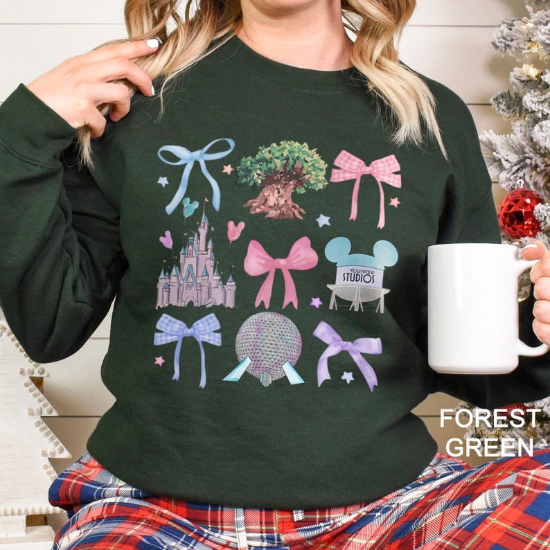 May include: Forest green sweatshirt with colorful graphic designs including bows, a castle, a tree, and a globe. The text "FOREST GREEN" is printed on the bottom right corner of the image.