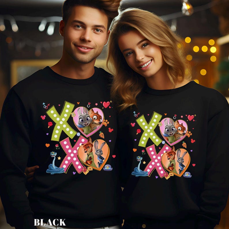 May include: Black sweatshirts featuring a colorful graphic with the text "XO" and heart-shaped illustrations of cartoon characters. The sweatshirts have long sleeves and a crew neck. The word "BLACK" is printed at the bottom.