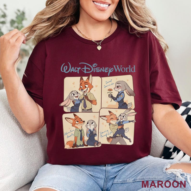 Puede incluir: Camiseta color granate con la inscripci&oacute;n "Walt Disney World" y cuatro paneles de dibujos animados de Nick Wilde y Judy Hopps de Zootopia. Los paneles incluyen las frases "Sweet Surrender", "Adventure Awaits" y "Dancing Through Life".