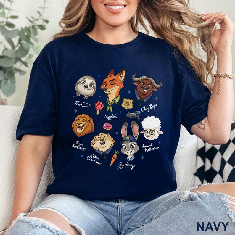 Pu&ograve; includere: T-shirt blu navy con illustrazioni di personaggi del film Zootropolis, tra cui Flash, Nick Wilde, Judy Hopps e Capo Bogo. La parola "NAVY" &egrave; stampata in basso sulla maglietta.