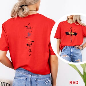 Pu&ograve; includere: T-shirt rossa con un disegno di drago. Il disegno include un drago con le ali spiegate, una luna crescente e stelle. La parola "RED" &egrave; stampata in rosso nella parte inferiore dell'immagine.