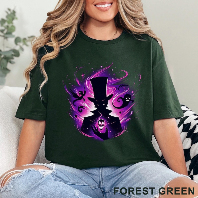 Puede incluir: Camiseta verde bosque con un gr&aacute;fico de una figura silueteada con sombrero de copa sosteniendo una calavera, rodeada de energ&iacute;a p&uacute;rpura y fantasmas. El texto "FOREST GREEN" est&aacute; impreso en la parte inferior.