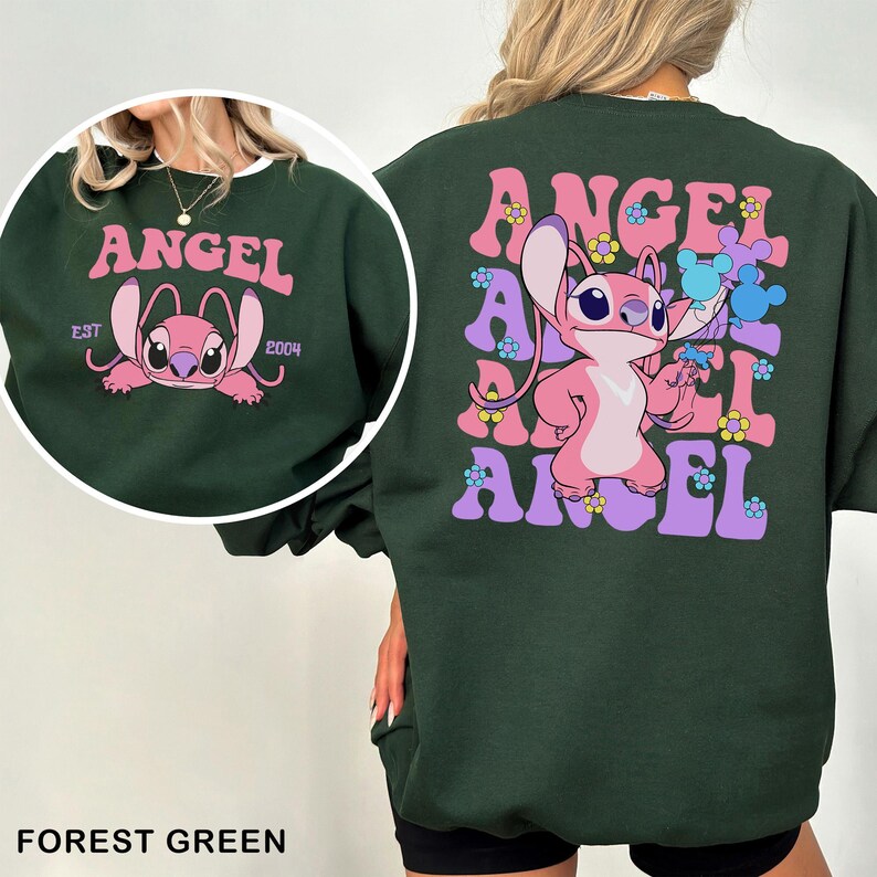 Puede incluir: Sudadera verde bosque con un dise&ntilde;o de personaje de dibujos animados rosa. La parte delantera presenta un gr&aacute;fico circular con la palabra "ANGEL" y el personaje. La parte trasera tiene un dise&ntilde;o "ANGEL" apilado con el personaje sosteniendo flores.